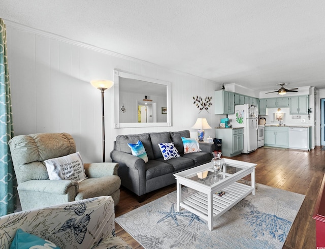 living area with ornamental molding, a textured ceiling, ceiling fan, and dark wood-style floors
