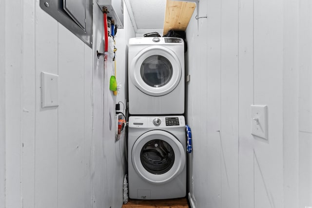 clothes washing area featuring stacked washer and dryer and laundry area