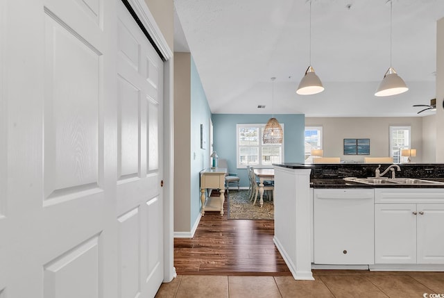 kitchen featuring pendant lighting, white cabinetry, white dishwasher, a sink, and light tile patterned flooring