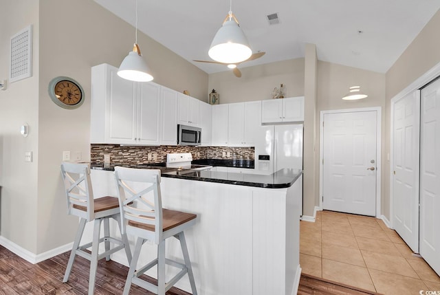 kitchen with white appliances, visible vents, white cabinets, dark countertops, and pendant lighting