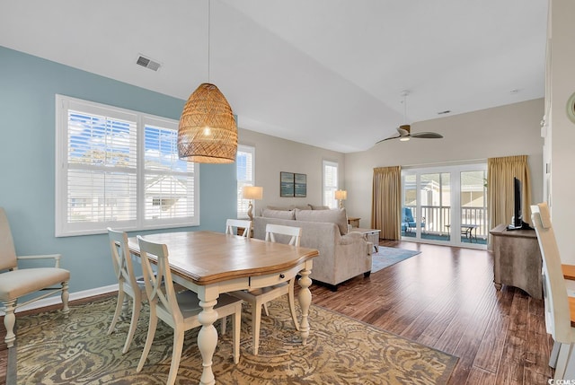 dining space with baseboards, visible vents, ceiling fan, wood finished floors, and vaulted ceiling