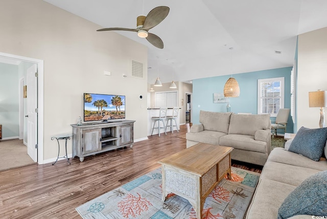 living room featuring ceiling fan, high vaulted ceiling, wood finished floors, visible vents, and baseboards