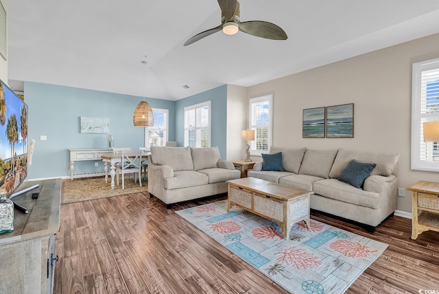 living area featuring a ceiling fan, plenty of natural light, baseboards, and wood finished floors