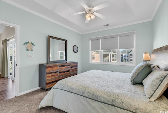 carpeted bedroom with ornamental molding, multiple windows, visible vents, and baseboards