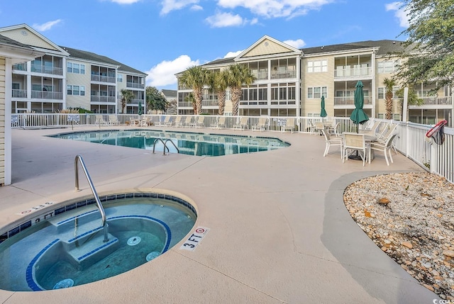 pool with fence, a community hot tub, and a patio