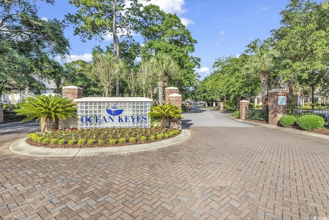 community / neighborhood sign featuring decorative driveway and fence