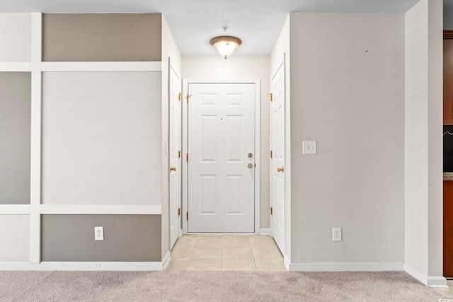 entryway with light carpet, baseboards, and light tile patterned floors