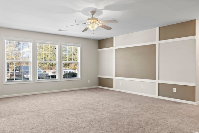 carpeted empty room with ceiling fan, visible vents, and baseboards