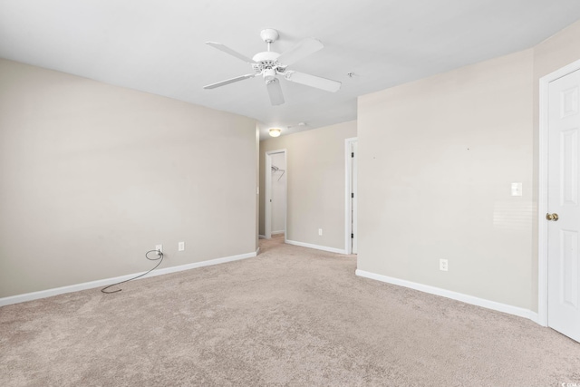 empty room with baseboards, ceiling fan, and light colored carpet