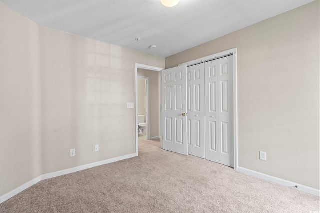 unfurnished bedroom with a closet, light colored carpet, and baseboards