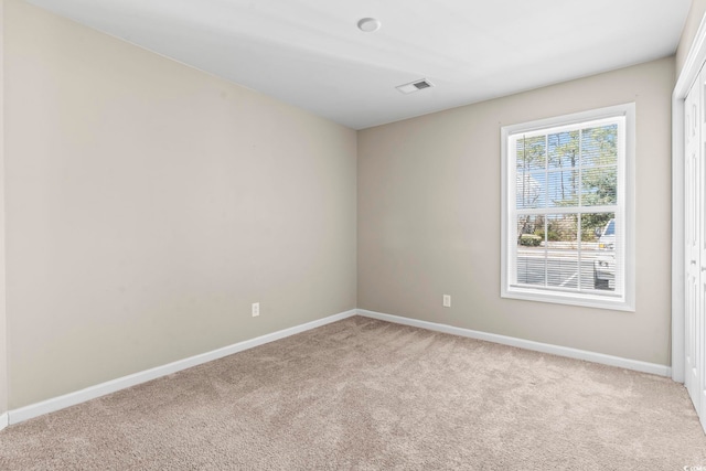 unfurnished room featuring carpet floors, visible vents, and baseboards