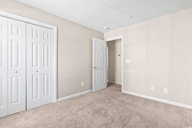 unfurnished bedroom with light carpet, baseboards, and a closet