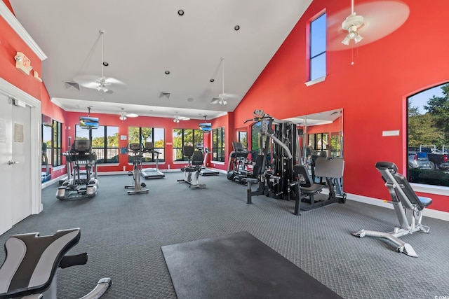 exercise room with ceiling fan, a high ceiling, visible vents, and baseboards