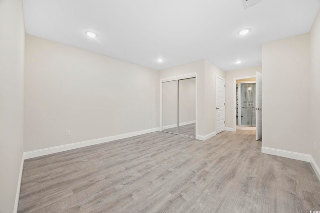 unfurnished bedroom featuring a closet, baseboards, wood finished floors, and recessed lighting