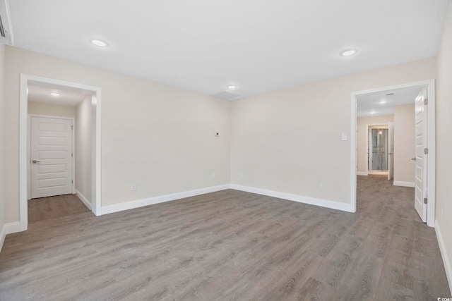 spare room featuring recessed lighting, baseboards, and wood finished floors