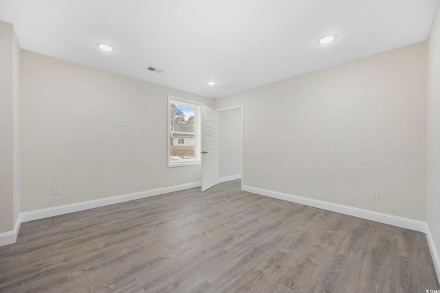 spare room featuring recessed lighting, baseboards, and wood finished floors