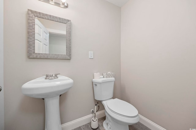 bathroom featuring toilet, baseboards, and wood finished floors