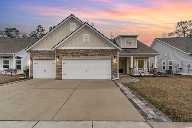 craftsman-style house featuring a porch, a garage, driveway, a yard, and board and batten siding