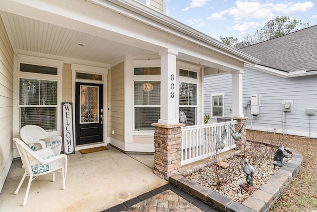 property entrance featuring a porch and a shingled roof