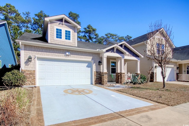 craftsman-style home featuring driveway, stone siding, and covered porch