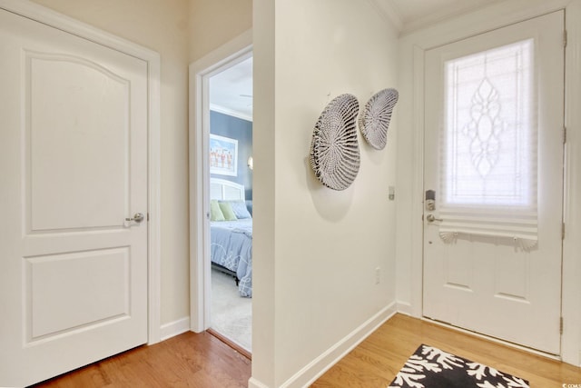 entrance foyer featuring baseboards, ornamental molding, and wood finished floors