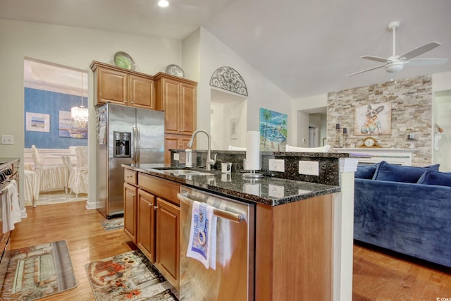 kitchen featuring open floor plan, stainless steel appliances, an island with sink, and a sink