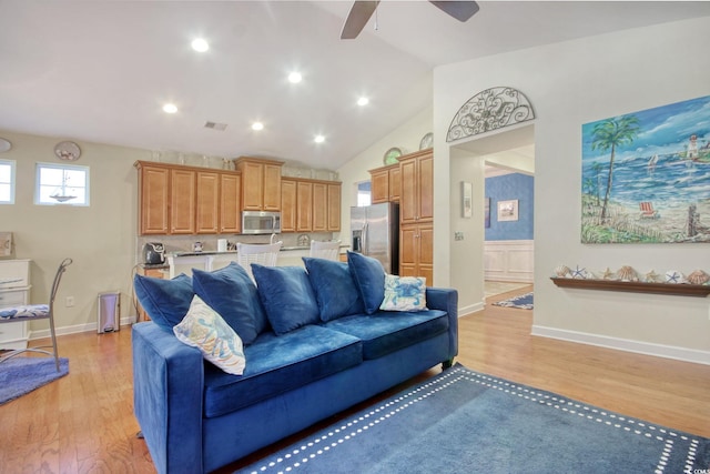 living area with lofted ceiling, light wood-style floors, ceiling fan, and baseboards