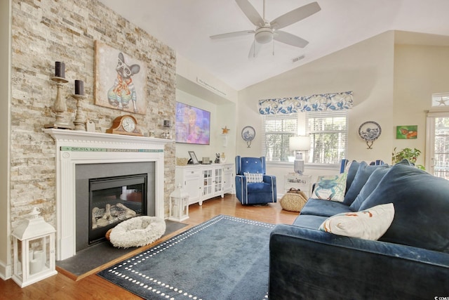 living area with ceiling fan, high vaulted ceiling, wood finished floors, visible vents, and a glass covered fireplace