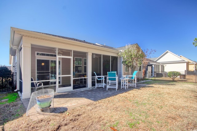 rear view of property featuring a sunroom, fence, a lawn, and a patio