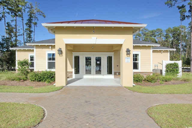 exterior space featuring metal roof, stone siding, french doors, and a standing seam roof