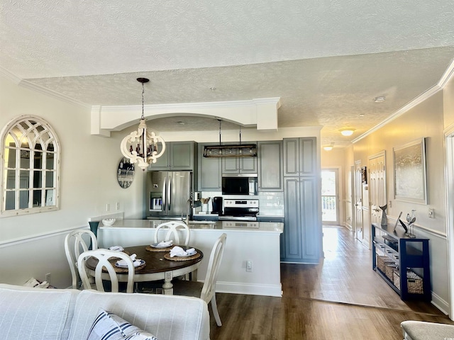 kitchen with crown molding, pendant lighting, stainless steel appliances, and dark wood-style flooring