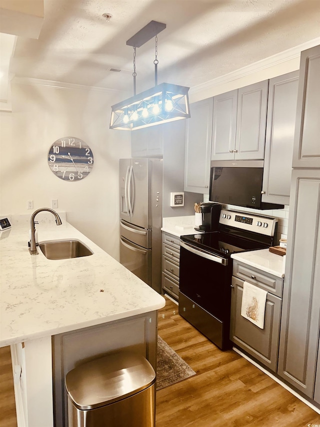 kitchen with light stone counters, a kitchen breakfast bar, hanging light fixtures, stainless steel appliances, and a sink