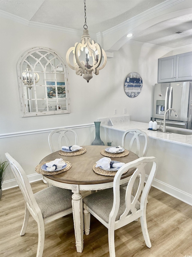 dining area with a notable chandelier, baseboards, wood finished floors, and crown molding