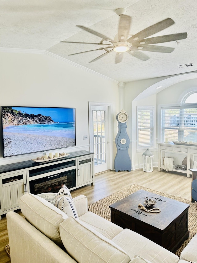 living area with light wood-style floors, lofted ceiling, visible vents, and a textured ceiling