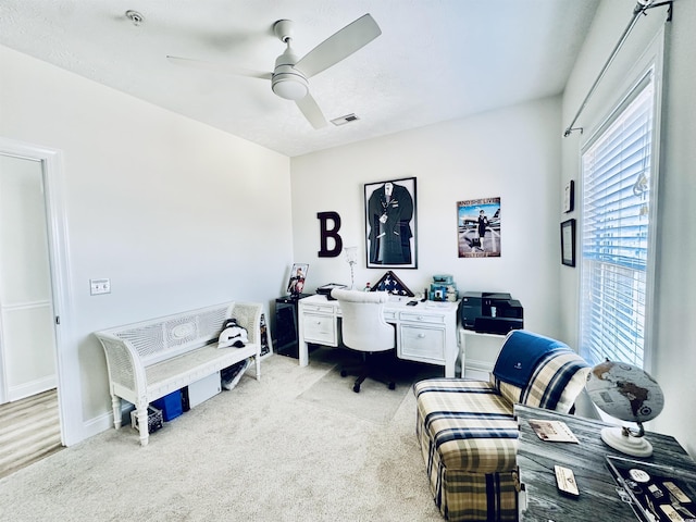 office featuring ceiling fan, visible vents, baseboards, and light colored carpet