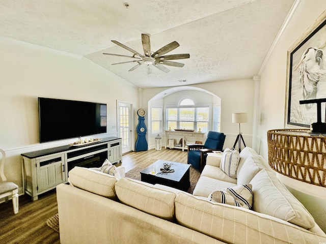 living area featuring lofted ceiling, a textured ceiling, arched walkways, wood finished floors, and a ceiling fan