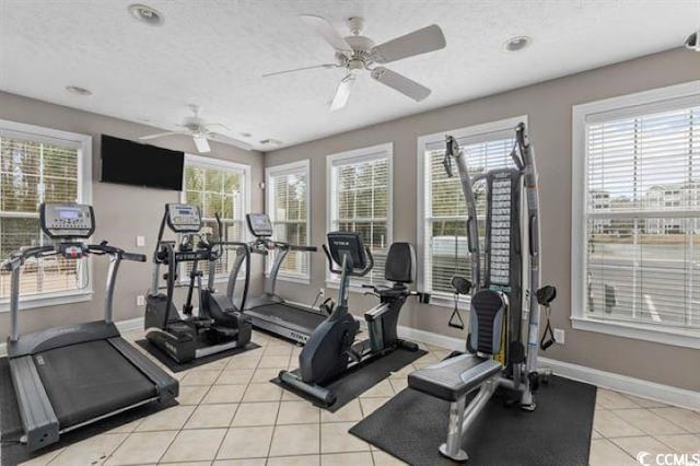 exercise room with a healthy amount of sunlight, light tile patterned flooring, a textured ceiling, and baseboards