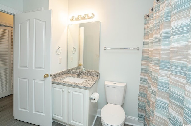 bathroom with a closet, baseboards, vanity, and toilet