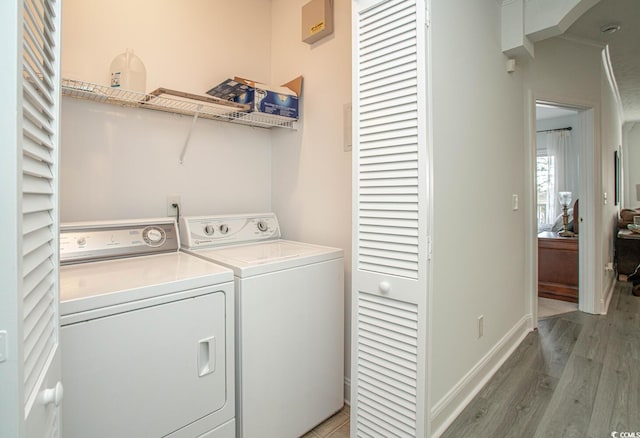 laundry area with laundry area, light wood finished floors, washing machine and clothes dryer, and baseboards