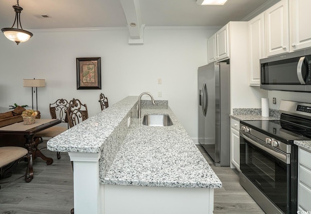 kitchen with light stone counters, hanging light fixtures, stainless steel appliances, white cabinetry, and a sink