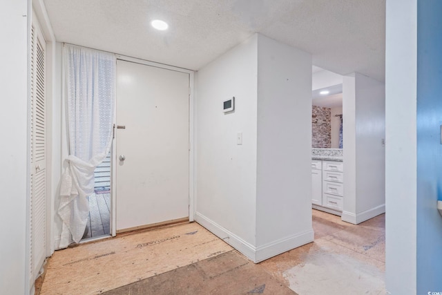 entryway featuring recessed lighting, a textured ceiling, and baseboards