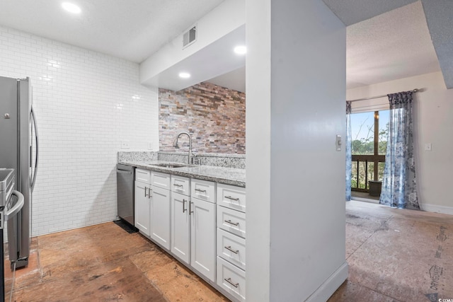 kitchen featuring visible vents, white cabinets, appliances with stainless steel finishes, light stone counters, and a sink