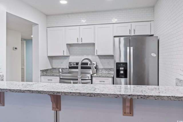 kitchen with a kitchen breakfast bar, stainless steel appliances, and white cabinets