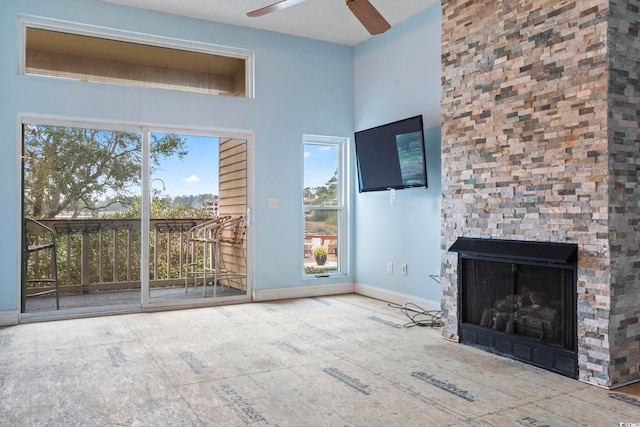 unfurnished living room with ceiling fan, a fireplace, and baseboards