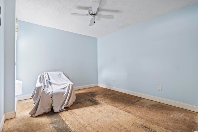 interior space with a textured ceiling, a ceiling fan, and baseboards