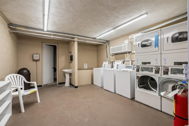 shared laundry area featuring concrete block wall, a garage, stacked washer and clothes dryer, a wall mounted air conditioner, and washer and dryer