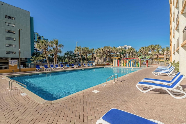 community pool with a patio area and fence