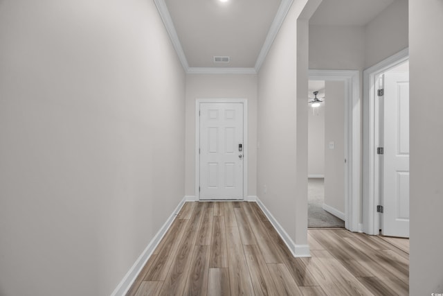 hall featuring visible vents, ornamental molding, light wood-style flooring, and baseboards