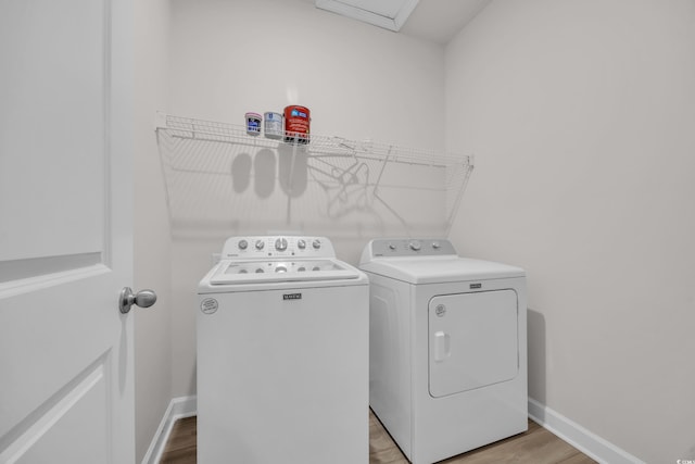 clothes washing area featuring baseboards, laundry area, washer and clothes dryer, and light wood-style floors