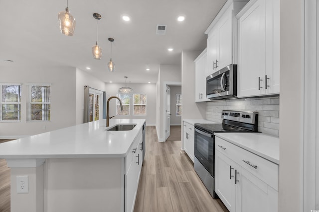 kitchen with a center island with sink, visible vents, appliances with stainless steel finishes, a sink, and backsplash